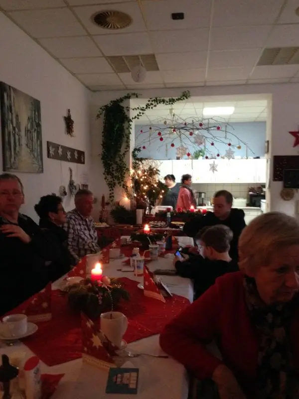 Bild: Impression der Weihnachtsfeier von 2017. Es ist ein gedeckter und geschmückter Tisch zu sehen, an dem Leute sitzen. Bild: Impression der Weihnachtsfeier von 2017. Es ist ein gedeckter und geschmückter Tisch zu sehen, an dem Leute sitzen.