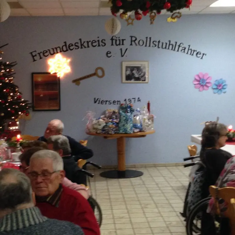 Bild: Impression der Weihnachtsfeier von 2017. Das Bild zeigt die geschmückte Stirnwand des Feierraumes, vor dem einige Leute sitzen und erzählen. Bild: Impression der Weihnachtsfeier von 2017. Das Bild zeigt die geschmückte Stirnwand des Feierraumes, vor dem einige Leute sitzen und erzählen.